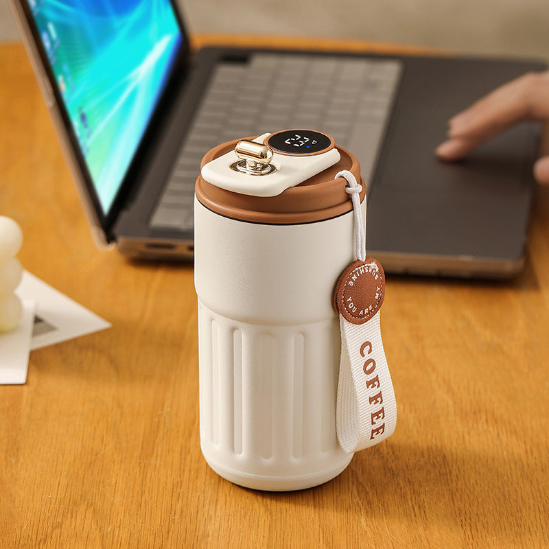 White and brown coffee thermos on a desk with a laptop in the background
