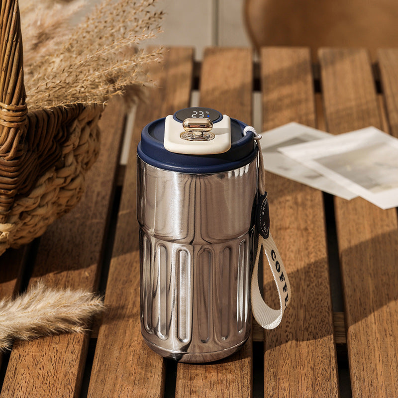 Silver tumbler with a blue lid on a wooden table