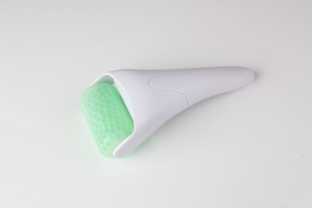 White and green skin care device on a light gray background