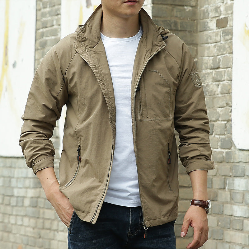 Person wearing a brown jacket over a white shirt with a brick wall background