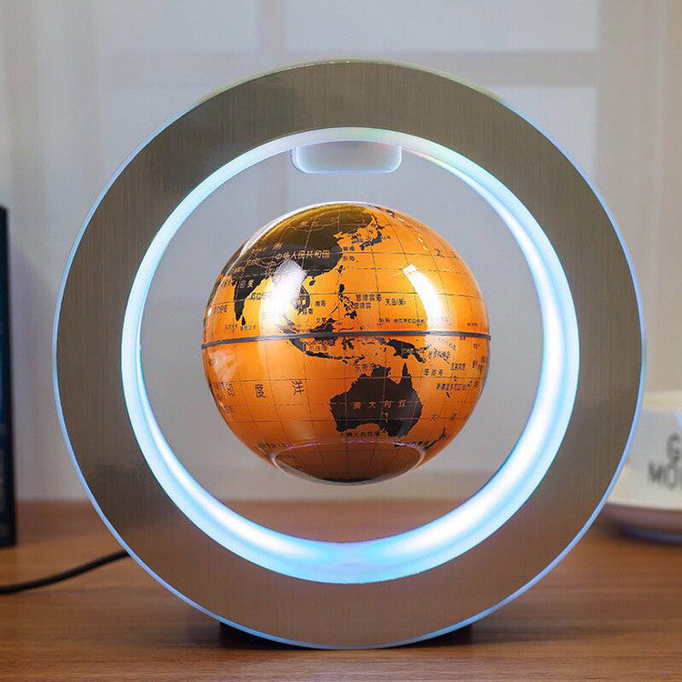 Orange globe levitating in a circular magnetic field on a wooden surface.