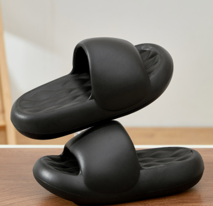 Black slippers on a wooden surface with a neutral background