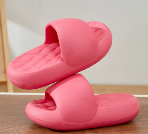 Pink slippers stacked on a wooden surface with a neutral background