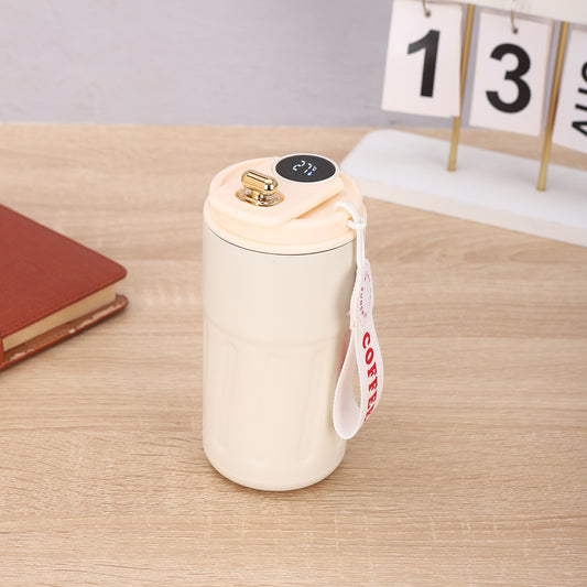 White ceramic mug with gold lid on a wooden surface, featuring a 'Coffee' tag.