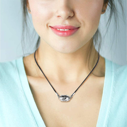 Woman wearing a necklace with a decorative pendant against a light background