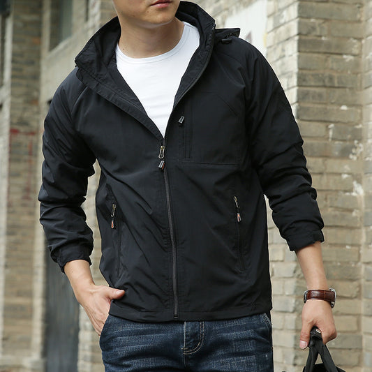Person wearing a black jacket in front of a brick wall